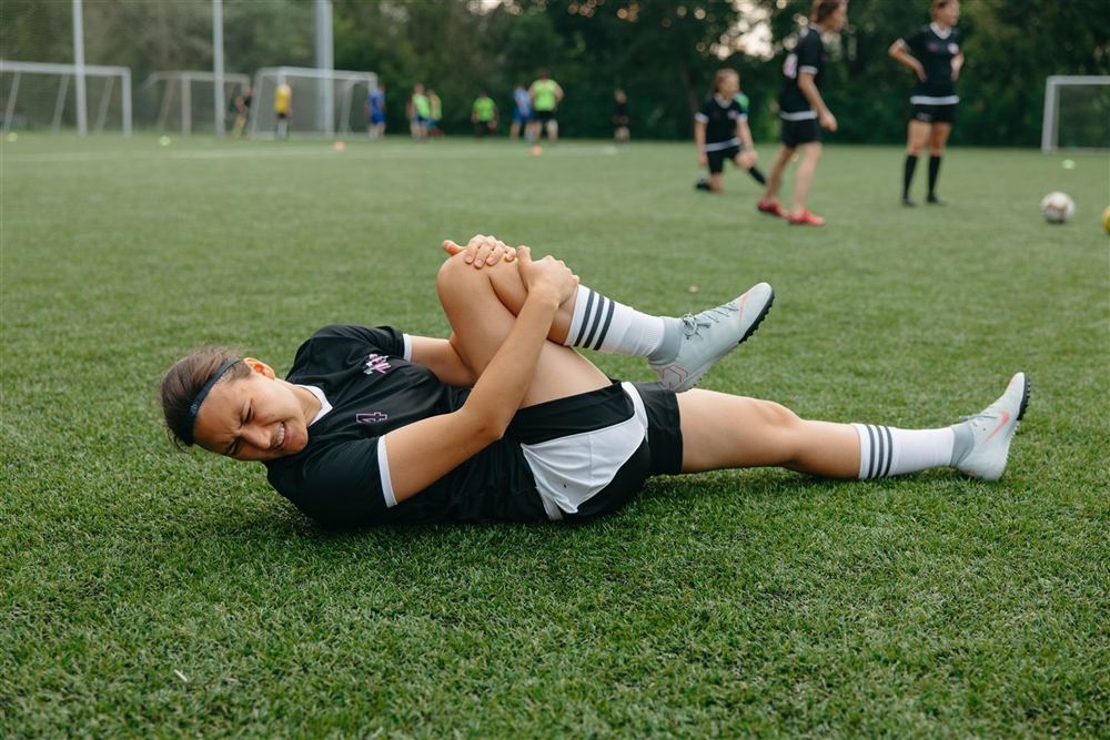 Athlete holding her knee after a sports injury on the field
