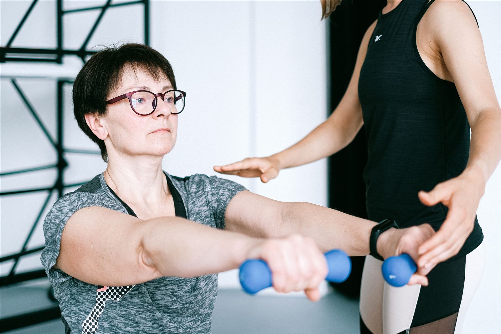 Physiotherapist guiding a patient through a shoulder exercise with light dumbbells